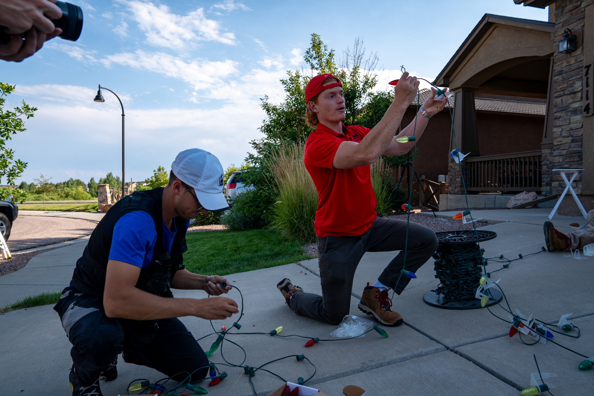 Solace Lighting installer hanging Christmas lights on a roofline